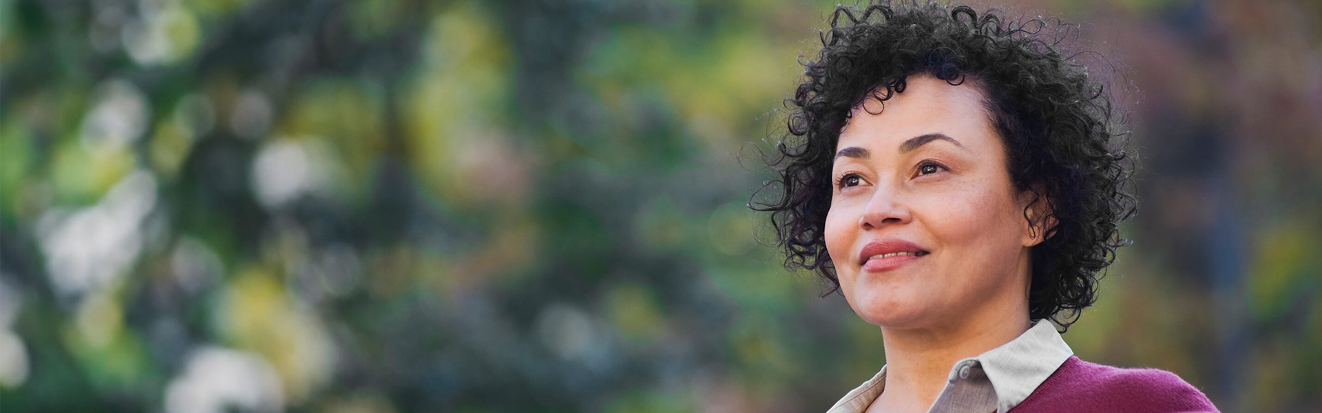 smiling woman with short curly hair looking into the distance